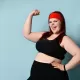 fatty-ginger-lady-red-headband-black-top-leggings-fitness-bracelet-showing-her-muscles-smiling-blue-background-fatty-ginger-179927939.jpg